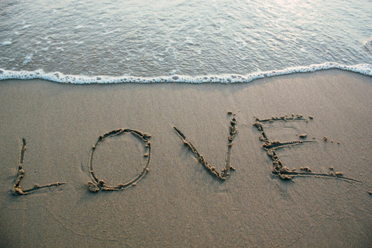 The word love written in sand at beach for blog about acts of love in our lives